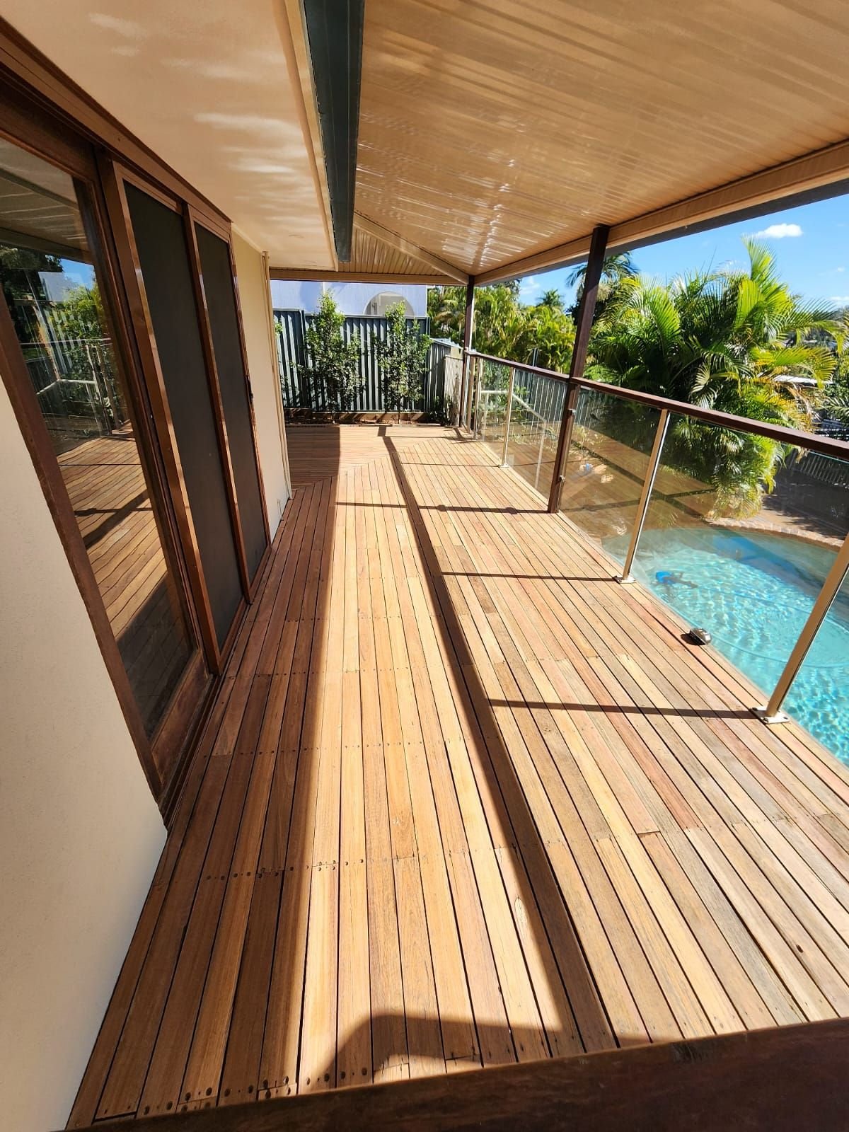 Restored timber pool deck with glass balustrade in Brisbane